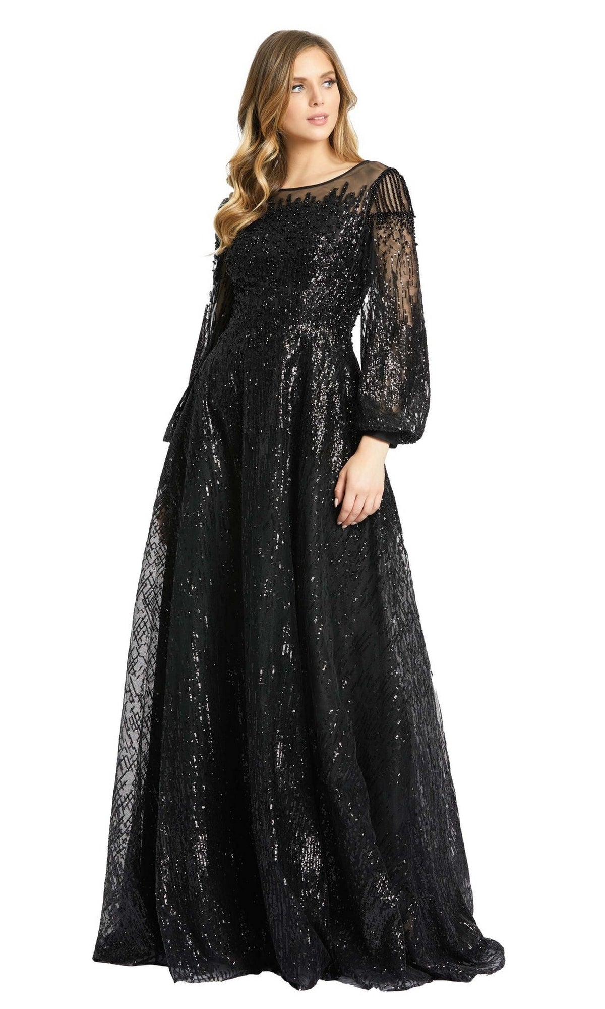 A woman wears the Mac Duggal 20307 Long Sleeve Sequin Formal Gown, a shimmering evening dress with sheer long sleeves and a slightly flared A-line silhouette.